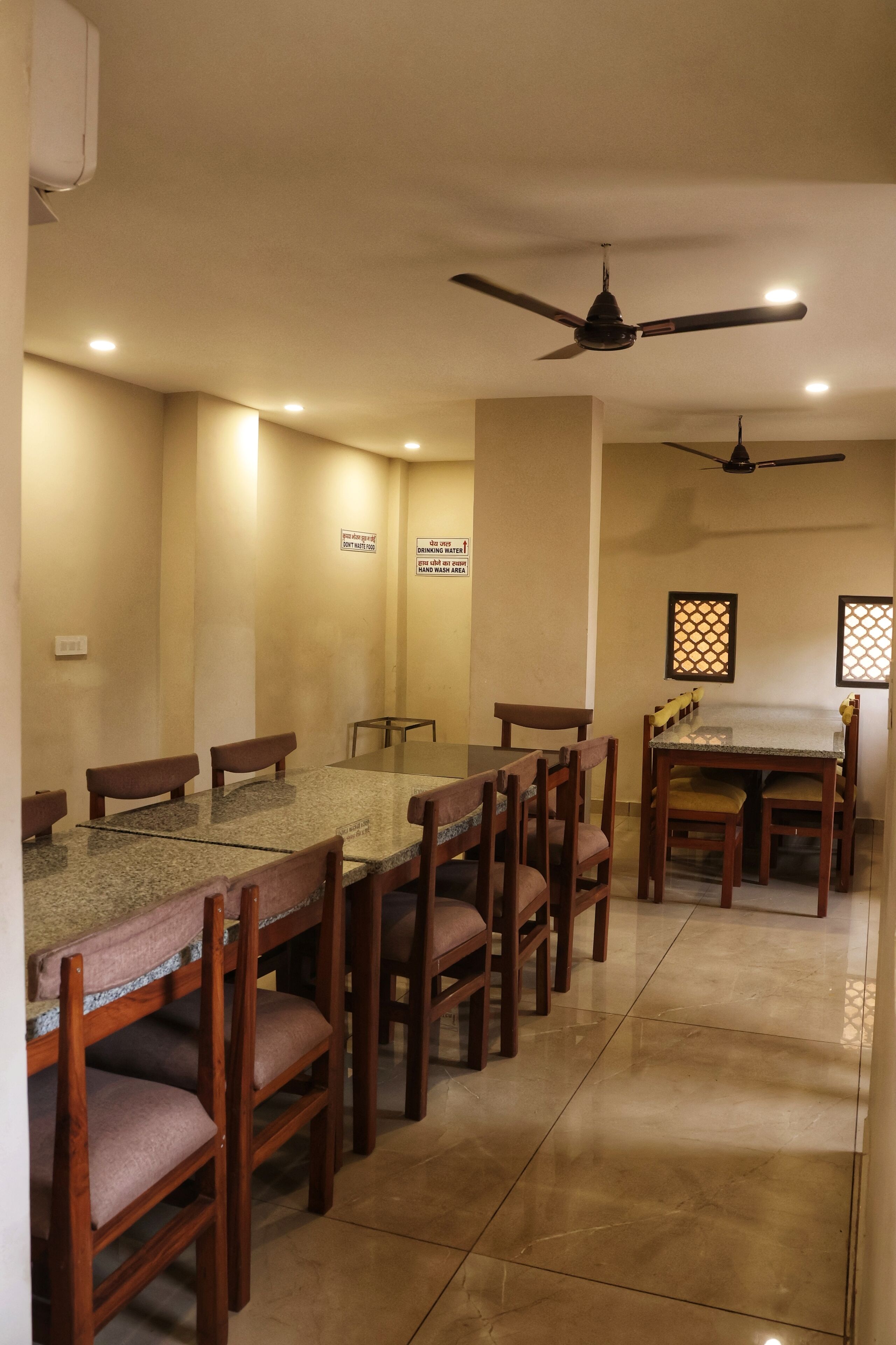 A dining area with a long table and chairs, ceiling fans, and wall-mounted signs.