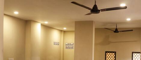 A dining area with a long table and chairs, ceiling fans, and wall-mounted signs.