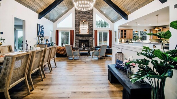 Een ruime woonkamer met een hoge plafond, een open haard en een eethoek met houten meubels.