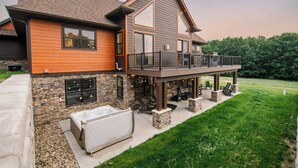 Een modern huis met een gevel van steen, een houten terras en een jacuzzi.
