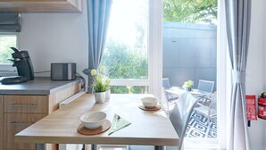 A modern kitchen with a wooden table, a coffee machine, and a view of the outdoors. - Tiny Haus Engel by Interhome (Beilngries)