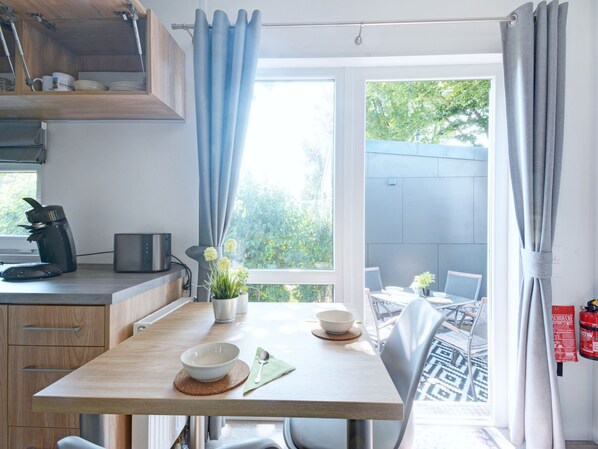 Enjoy a meal for two at the dining table, complete with a coffee maker and a potted plant.