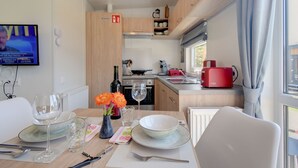 A modern kitchen with wooden cabinets, a red coffee maker, and a dining area with a table set for two. - Tiny Haus Sonnendeck by Interhome (Beilngries)