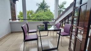 A balcony with a glass door, a table, and four purple chairs. - Melody Riverside Homestay  (Hue)