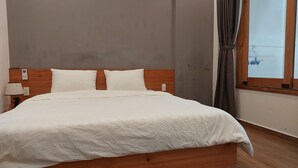 A neatly made bed with a wooden headboard, a bedside lamp, and a window with curtains. - Melody Riverside Homestay  (Hue)