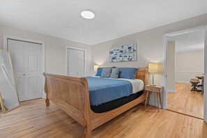 A bedroom with a wooden bed, a bedside table with a lamp, and a wall-mounted artwork. - Big family friendly, Deck, Pool Table, Propane Grill & Fire Pit! (Hot Springs)