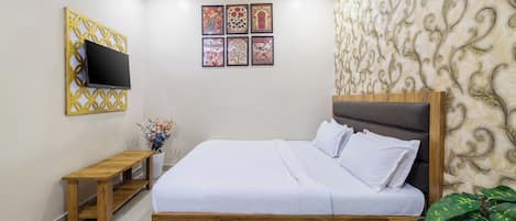 A bedroom with a bed, a TV, a bench, and a wall with decorative panels.