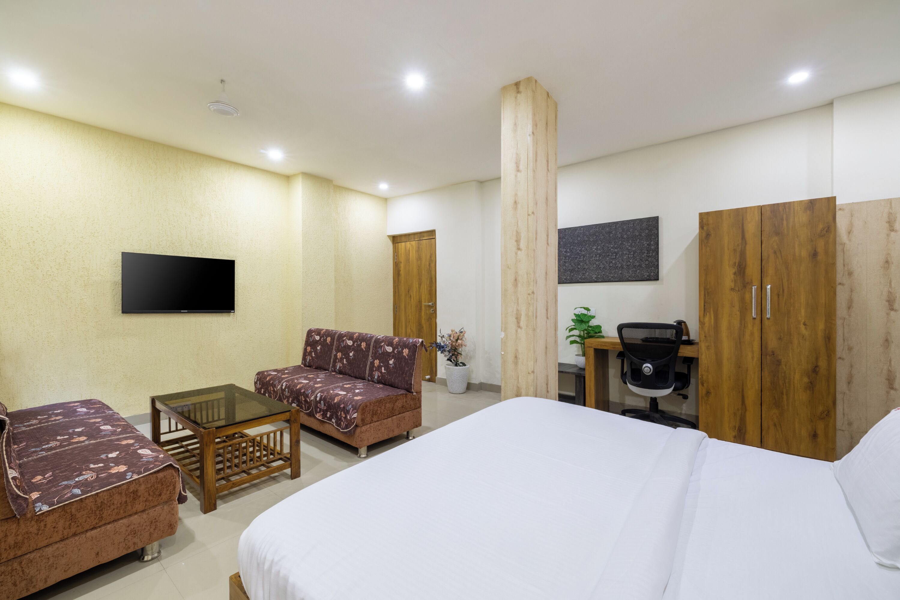 Ein Hotelzimmer mit einem Bett, zwei Schlafsofas, einem kleinen Tisch, einem Fernseher und einem Schreibtisch mit einem Stuhl.