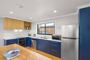 Una cocina moderna con armarios azules, electrodomésticos de acero inoxidable y una mesa de comedor de madera.