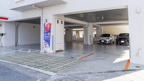 En moderne bygning med parkeringsdækning, et skilt og to parkerede biler.