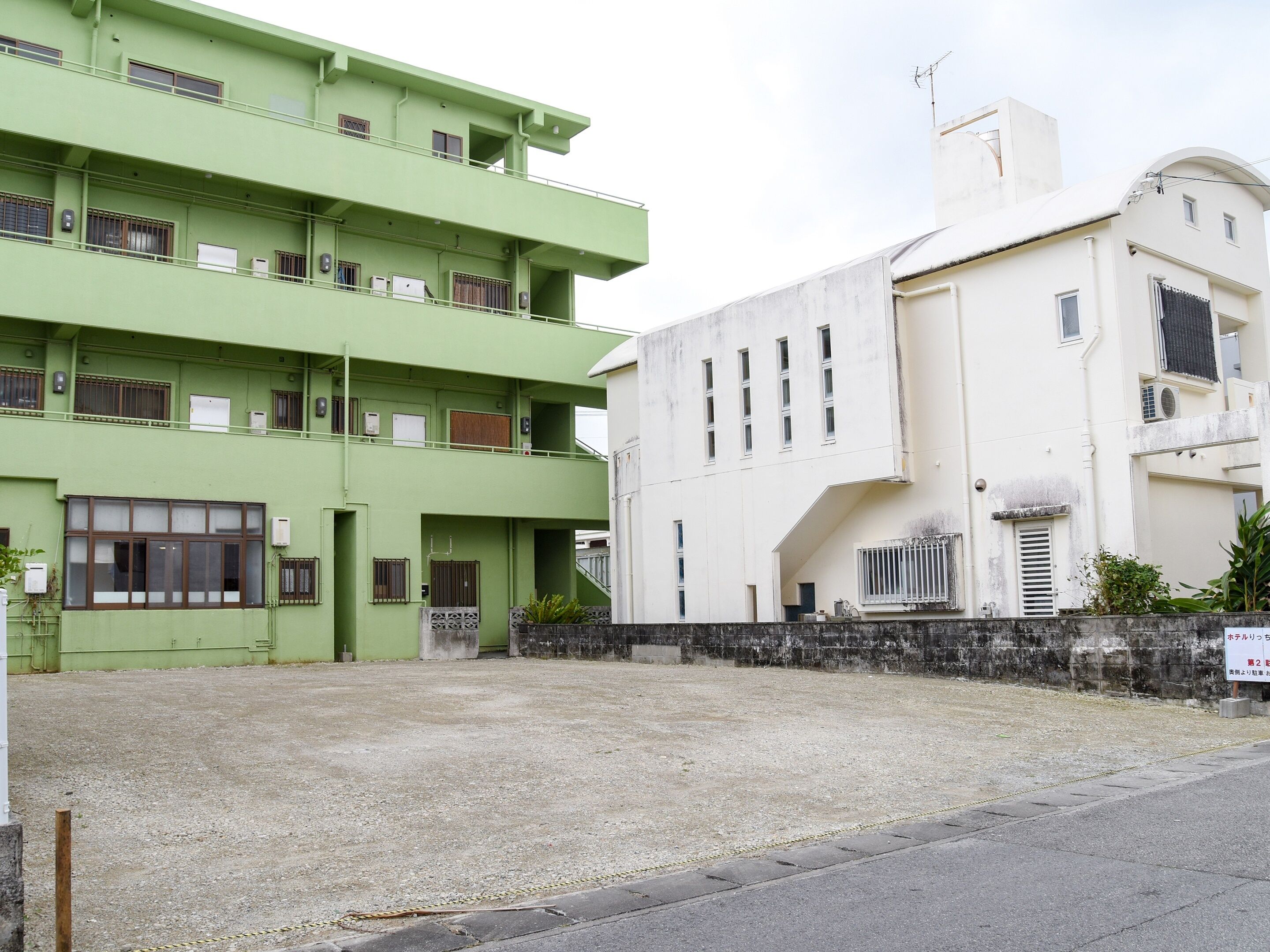 A multi-story building with a green facade and a white building adjacent to it.