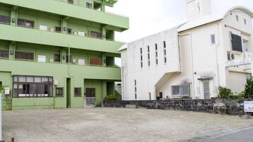 Un edificio de varios pisos con fachada verde y un edificio blanco contiguo.