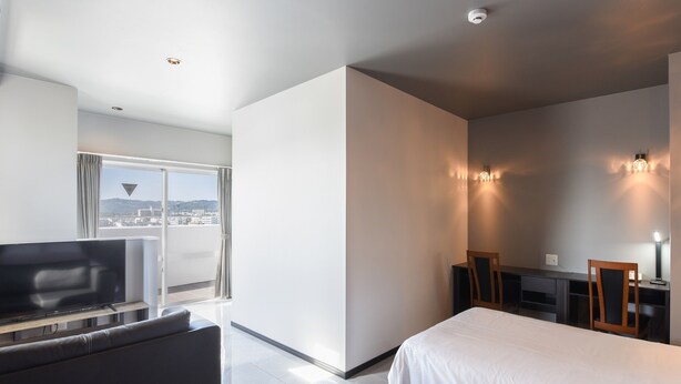 Et moderne hotelværelse med en stor seng, en sofa, et skrivebord og et fjernsyn.