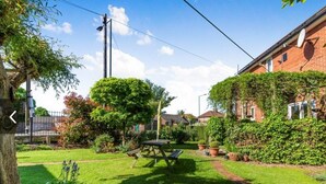 Un jardin bien entretenu, avec une table de pique-nique, un arbre et un bâtiment en briques.