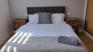 Une chambre à coucher comprenant un lit, deux tables de chevet, une tête de lit et une fenêtre.