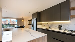 A modern kitchen with a large island, dark cabinetry, and a city view. - Spectacular 3BR flat with great view close to Provenza (Medellín)