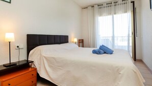 A hotel room with a bed, a nightstand, a lamp, a ceiling fan, and a window with curtains. - Apartment Arquus by Interhome (Salou)