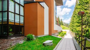 Um edifício moderno com grandes janelas, um caminho pavimentado e um jardim bem cuidado.