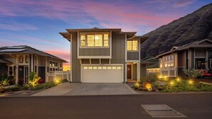 Een modern huis met twee verdiepingen, een garage, omringd door aangelegde tuinen en een oprit.