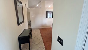 Un pasillo con una mesa y sillas negras, un cuadro en la pared y una ventana con vistas.