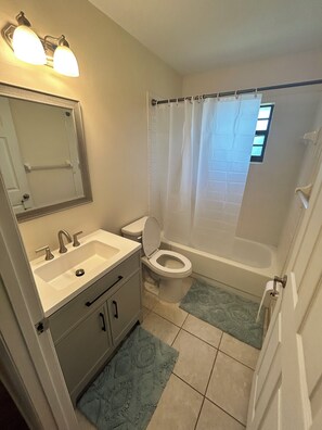 A bathroom with a sink, mirror, toilet, and bathtub.