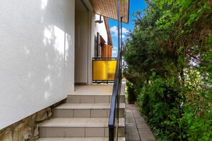A staircase leading to a balcony with a view of greenery and a clear sky.