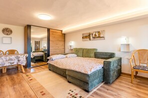 A bedroom with a bed, a chair, a table, and a mirror.