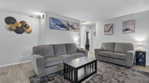 Ein modernes Wohnzimmer mit zwei grauen Sofas, einem Couchtisch und Wanddekoration.