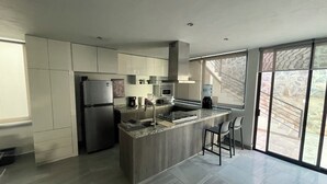 Een moderne keuken met een centraal eiland, roestvrijstalen apparatuur en een groot raam met uitzicht op de omgeving.