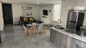 Een moderne keuken met een centraal eiland, roestvrijstalen apparatuur en een eethoek met grijze stoelen.