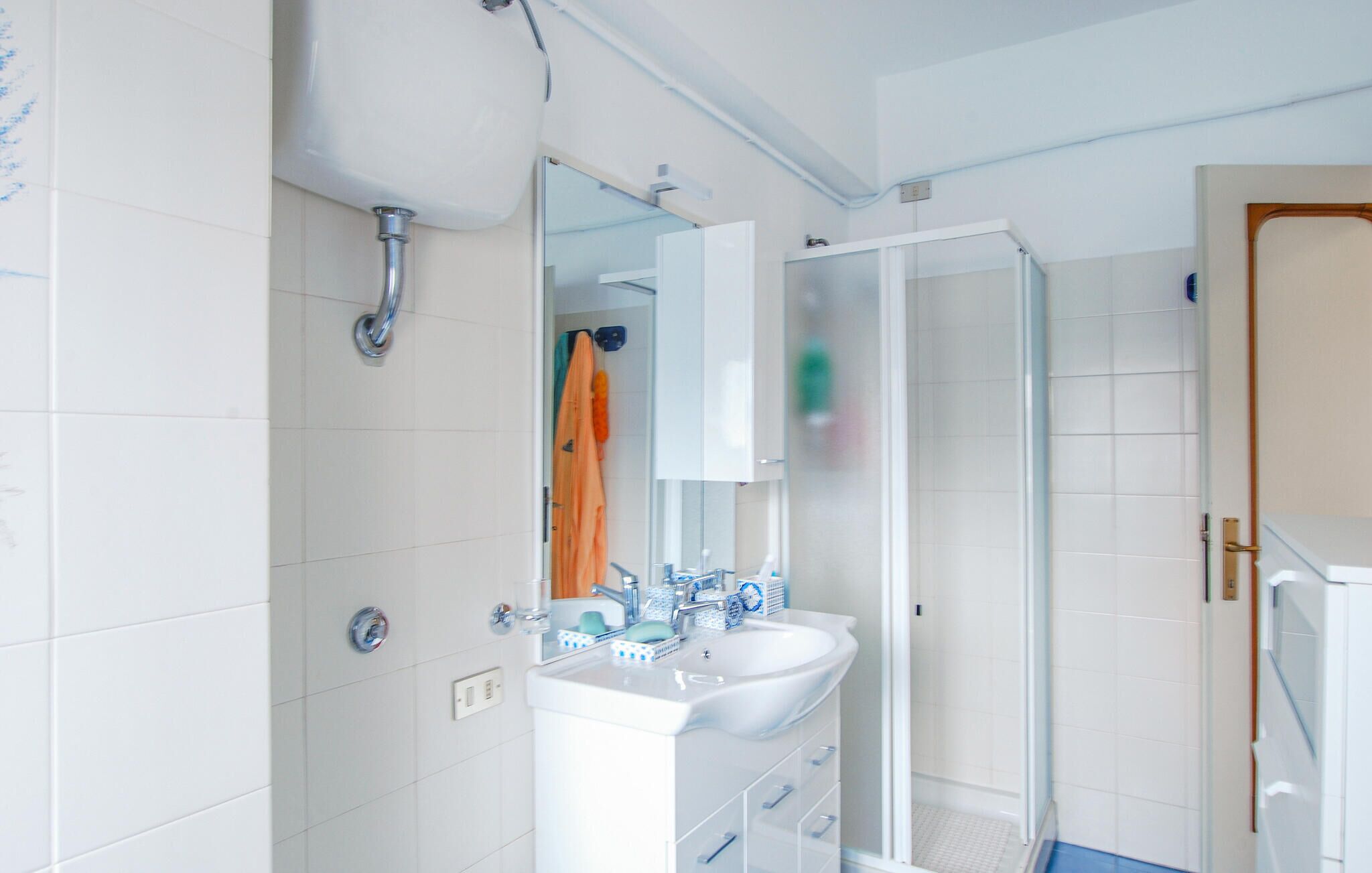 A bathroom with a white sink, mirror, and shower.