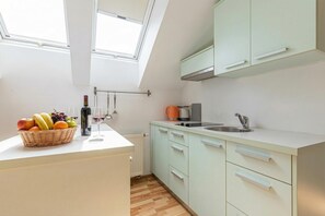 Una cocina moderna con tragaluz, una cesta de frutas, una botella de vino y una cafetera.