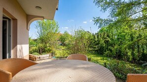 A patio with wicker furniture, a view of a garden, and a building entrance. - Lavrič Studio 1 at Lake Bloke, Bloke, Slovenia (Bloke)