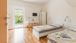 A bedroom with two beds, a desk, a television, and a wardrobe. - Lavrič Studio 1 at Lake Bloke, Bloke, Slovenia (Bloke)