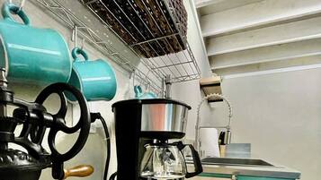 Een keuken met een koffiezetapparaat, een waterkoker en een spoelbak.