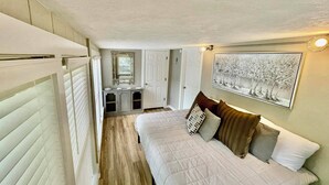 A bedroom with a bed, a dresser, a mirror, and a painting on the wall. - The Eclectic - "Treehouse" and "Bunkhouse" (Bryan)