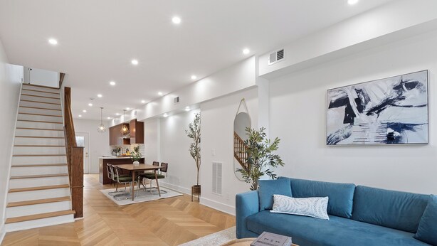 A modern living room with a blue sofa, a wooden coffee table, and a staircase leading to an upper level.