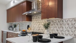 A modern kitchen with wooden cabinets, a white countertop, and a geometric backsplash.