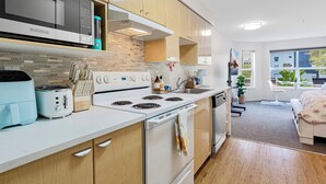 Une cuisine moderne équipée d’un four à micro-ondes, d’un grille-pain et d’une cuisinière. On y trouve un évier et une fenêtre donnant sur l’extérieur.