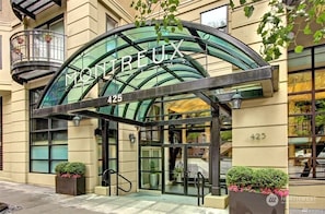 Entrada de um edifício moderno com arco de vidro, o número 425 e uma placa com 'Montréalux'.