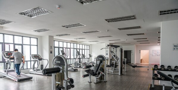 Un gimnasio con cintas de correr, máquinas de pesas y mancuernas.