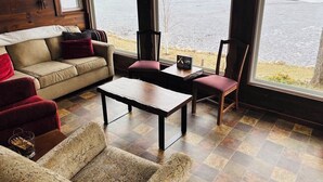Un cuarto acogedor con sofá, sillones, una mesita de centro y vistas a un lago a través de amplias ventanas.