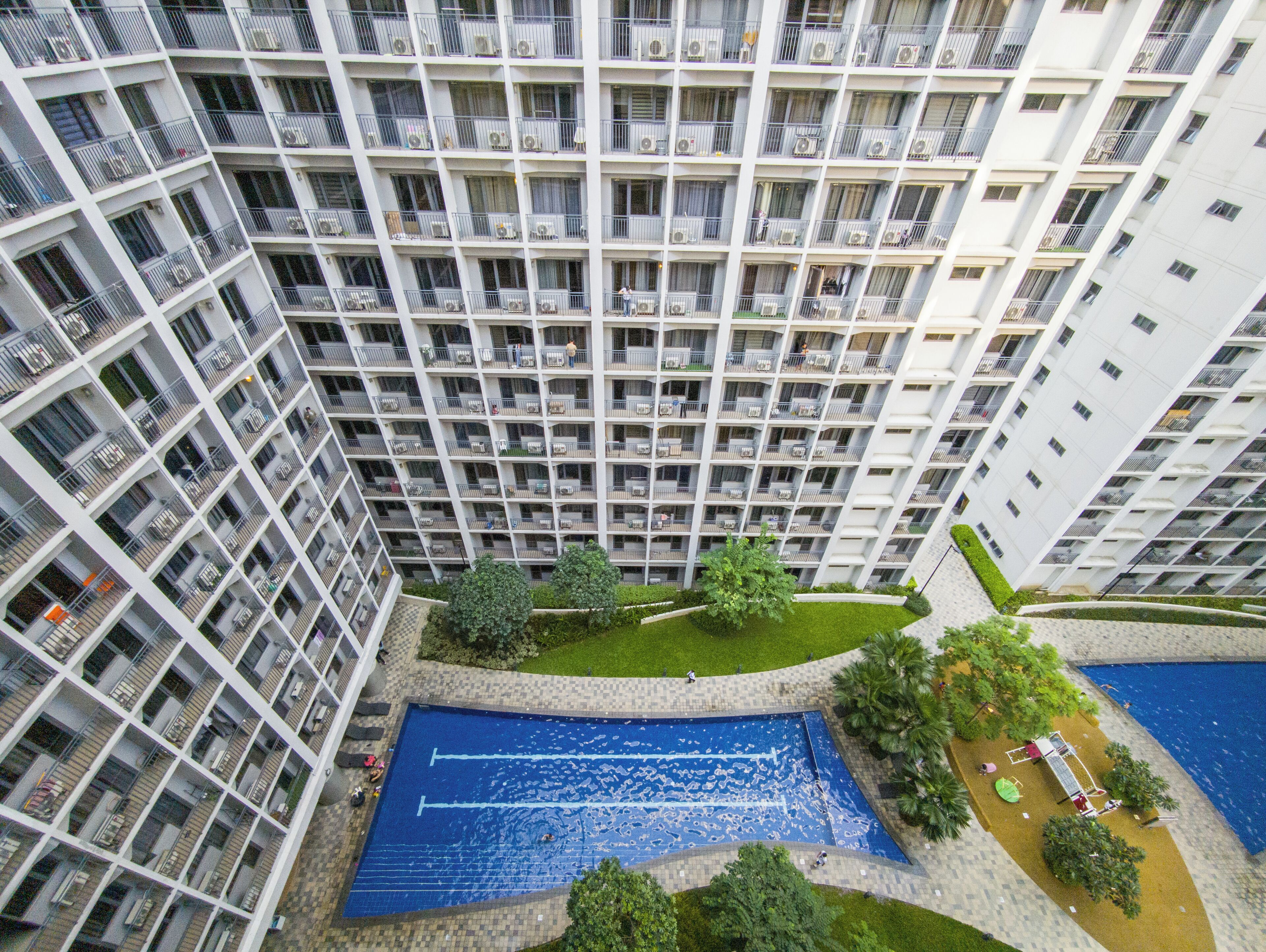 A high-rise building with multiple balconies and a central courtyard with a swimming pool.