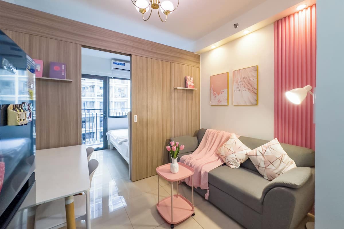 Una habitación de hotel moderna con un sofá, una mesita con un florero, un escritorio y un armario.