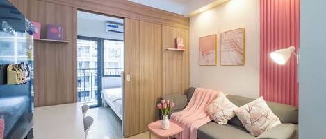 Una habitación de hotel moderna con un sofá, una mesita con un florero, un escritorio y un armario.