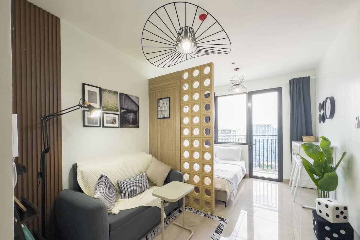 Una sala de estar moderna con un sofá, una mesita, un separador decorativo y vistas de la ciudad a través de la ventana.