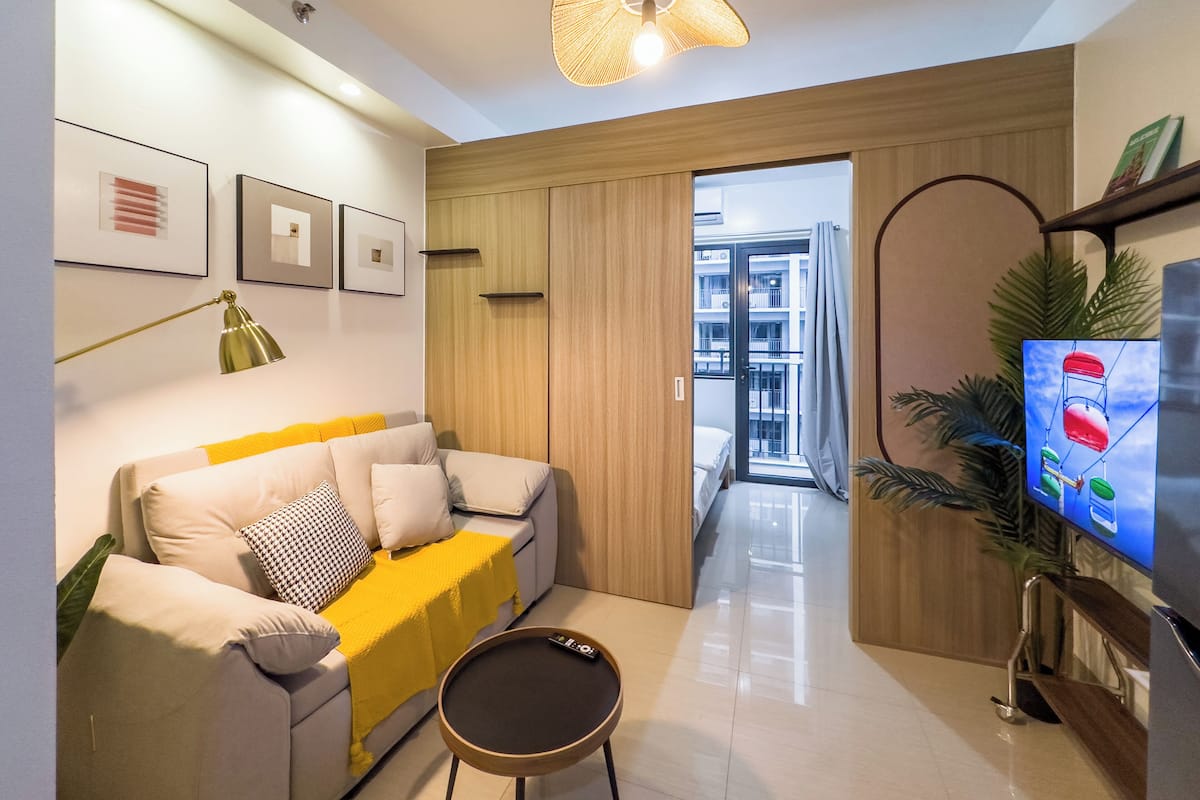 Una sala de estar moderna con un sofá, una mesa de centro, un televisor y un ventanal grande.