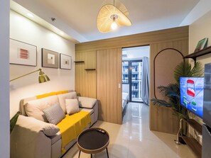 Una sala de estar moderna con un sofá, una mesa de centro, un televisor y un ventanal grande.