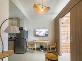 A modern kitchen with a refrigerator, microwave, and a dining area with a table and chairs.
