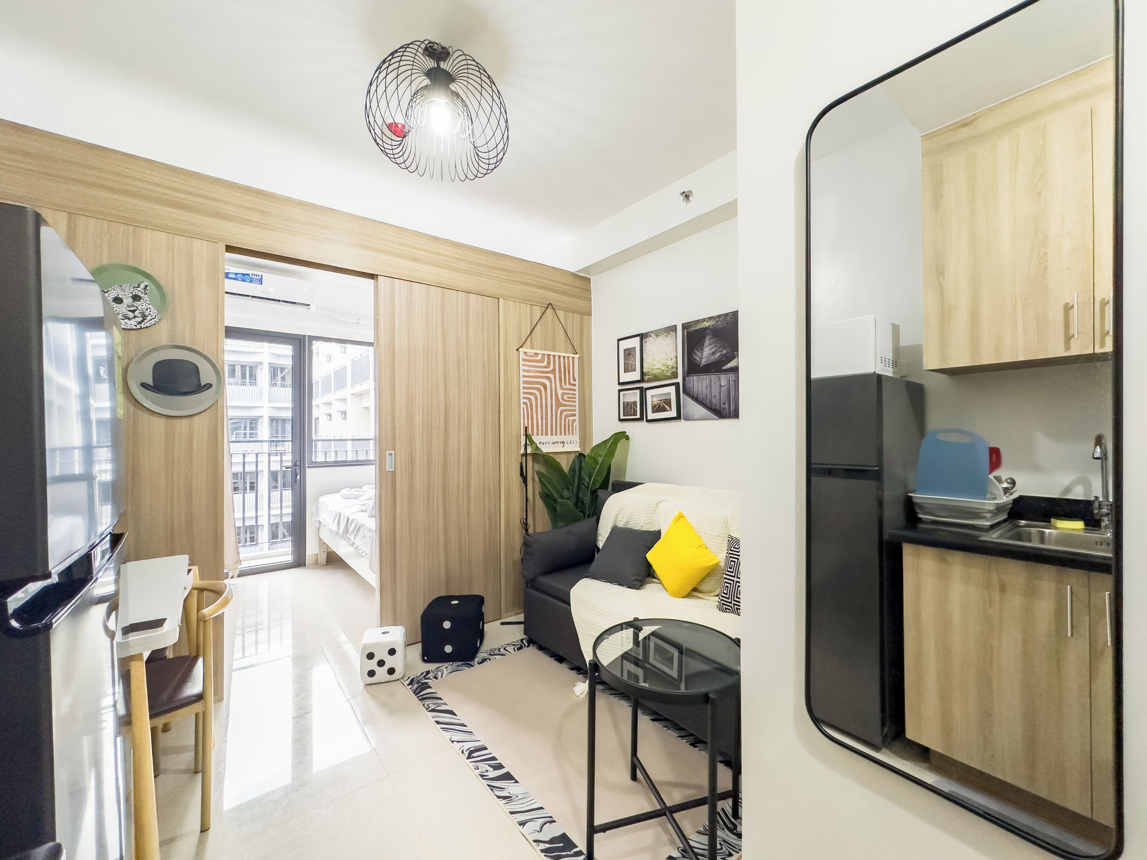 Un appartement moderne comprenant une cuisine, un coin repas et un salon. Il est doté d’une grande fenêtre, d’un ventilateur de plafond et d’un réfrigérateur.